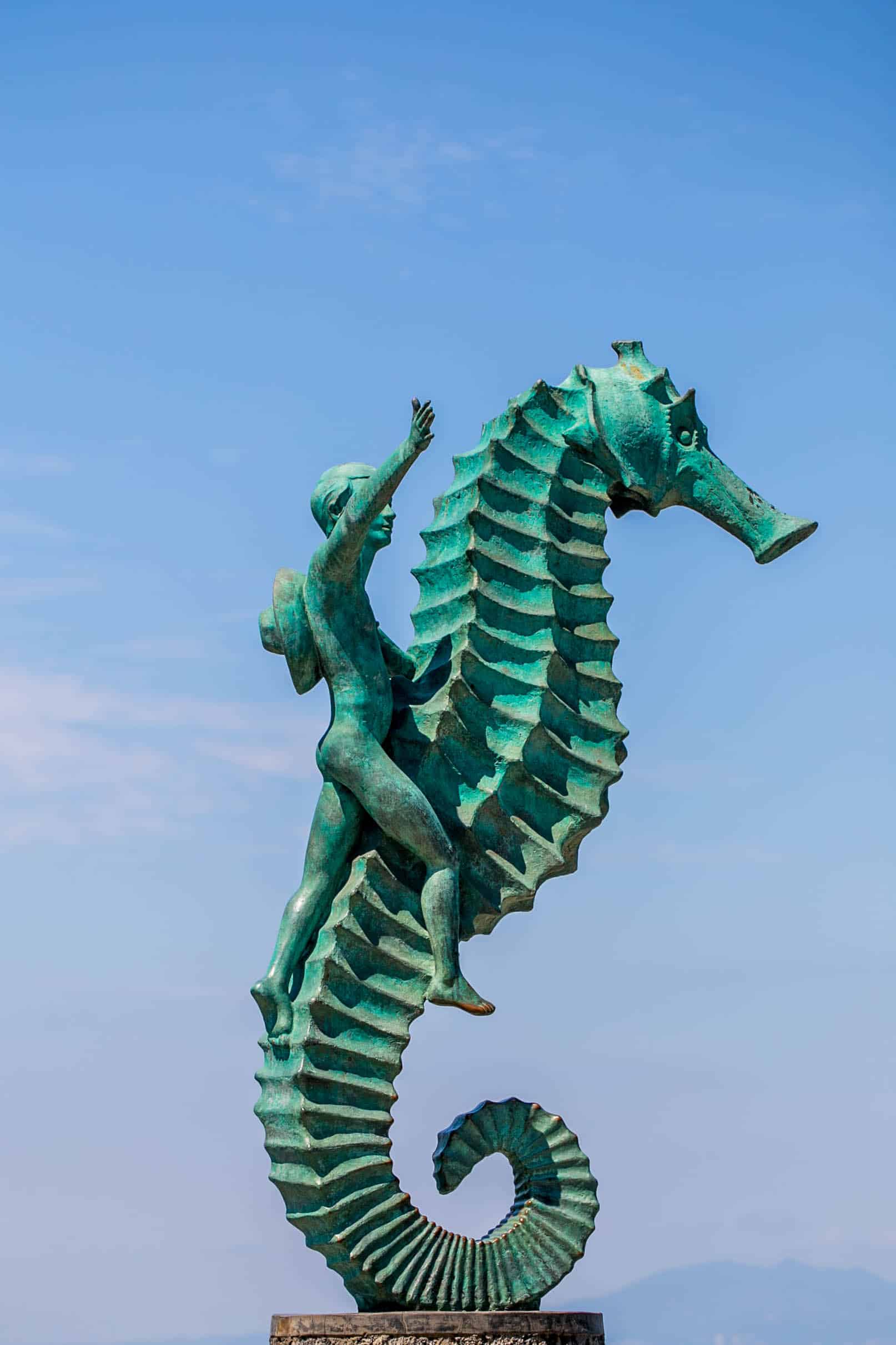 green seahorse statue with a boy riding on it 