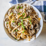 A bowl of creamy Beef Stroganoff Fettuccine topped with sliced green onions.