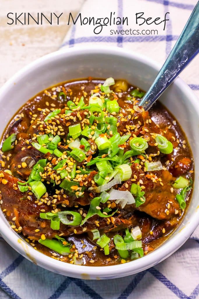 Mongolian beef stew in a bowl with green onions on it and a spoon in it. 