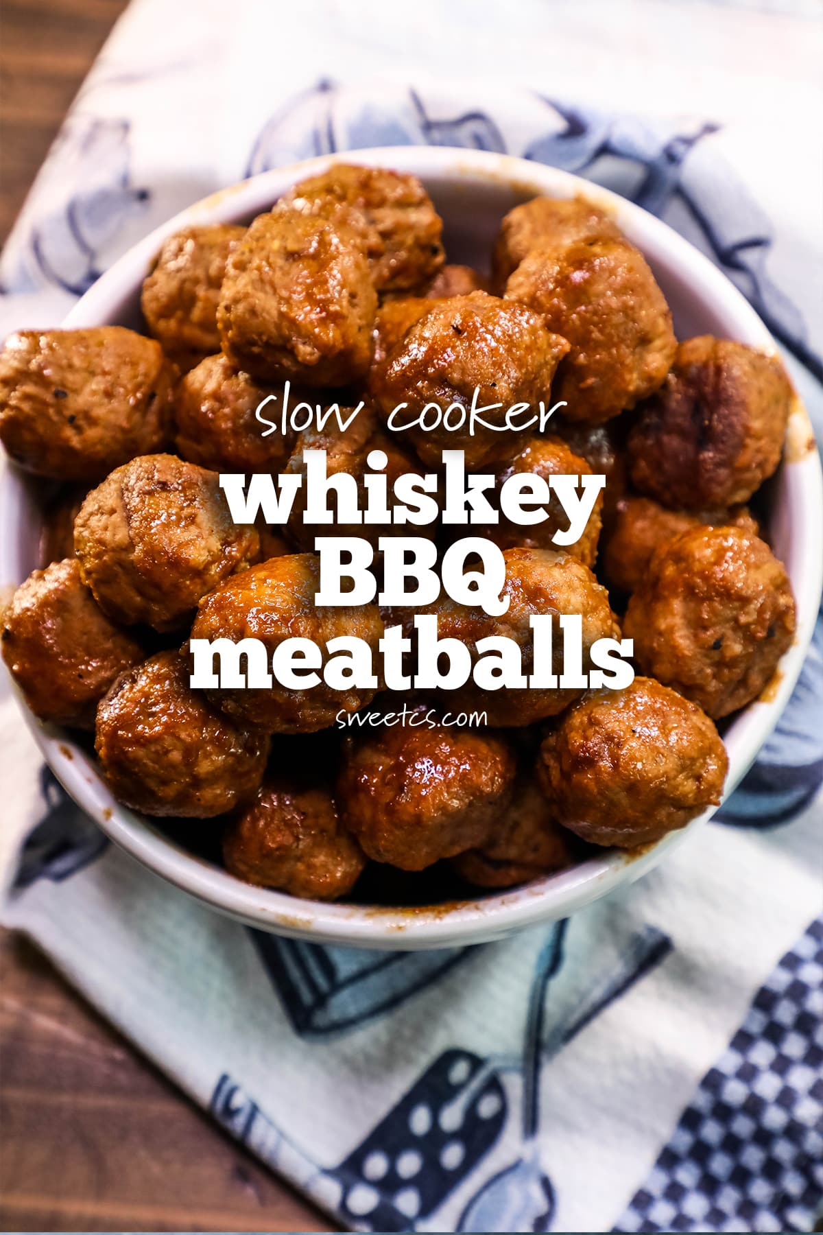 bowl of bbq meatballs with a blue and white towel in the background, whiskey bbq meatballs written on them. 