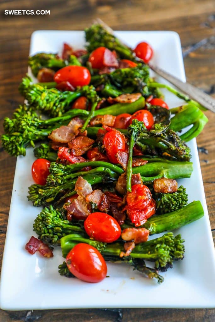 picture of a white plate with broccolini, bacon, and cherry tomatoes on it. 