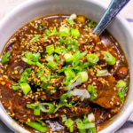 A bowl of skinny Mongolian beef stew with green onions and sesame seeds.