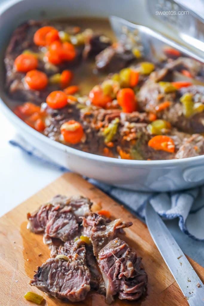 beef ranch pot roast with carrots and gravy some beef on a cutting board.