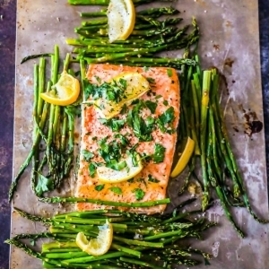 Salmon and asparagus with lemon wedges baked on a sheet.