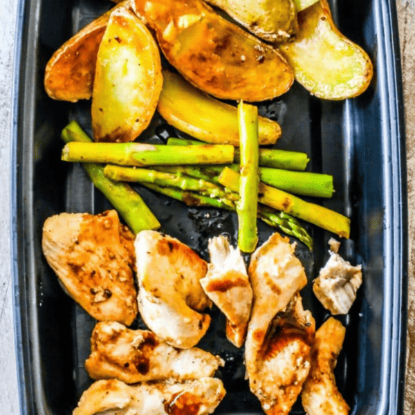 Instant pot balsamic chicken and vegetables bowls with roasted potatoes and asparagus on a black plate.