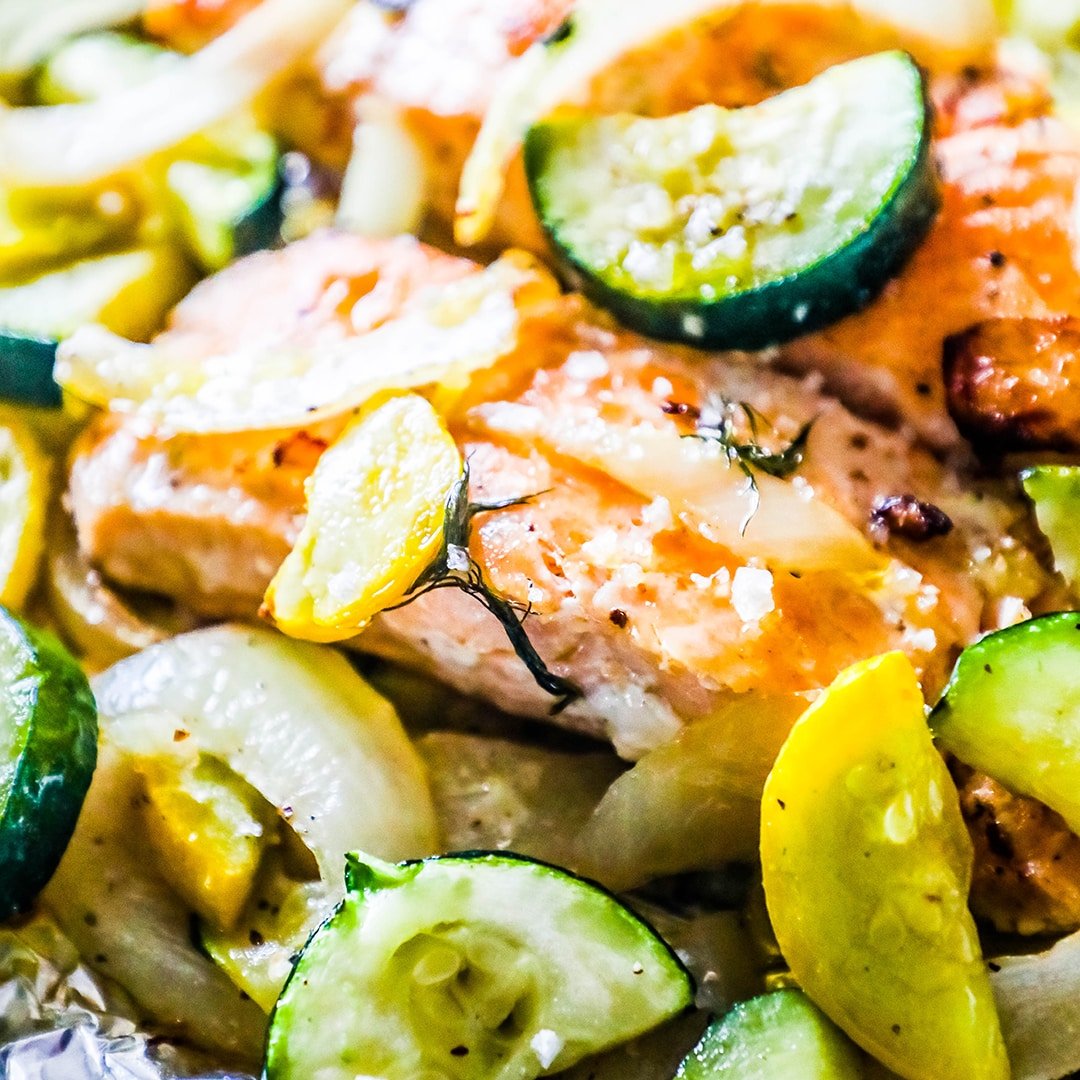 salmon with dill surrounded by zucchini, squash, and onion