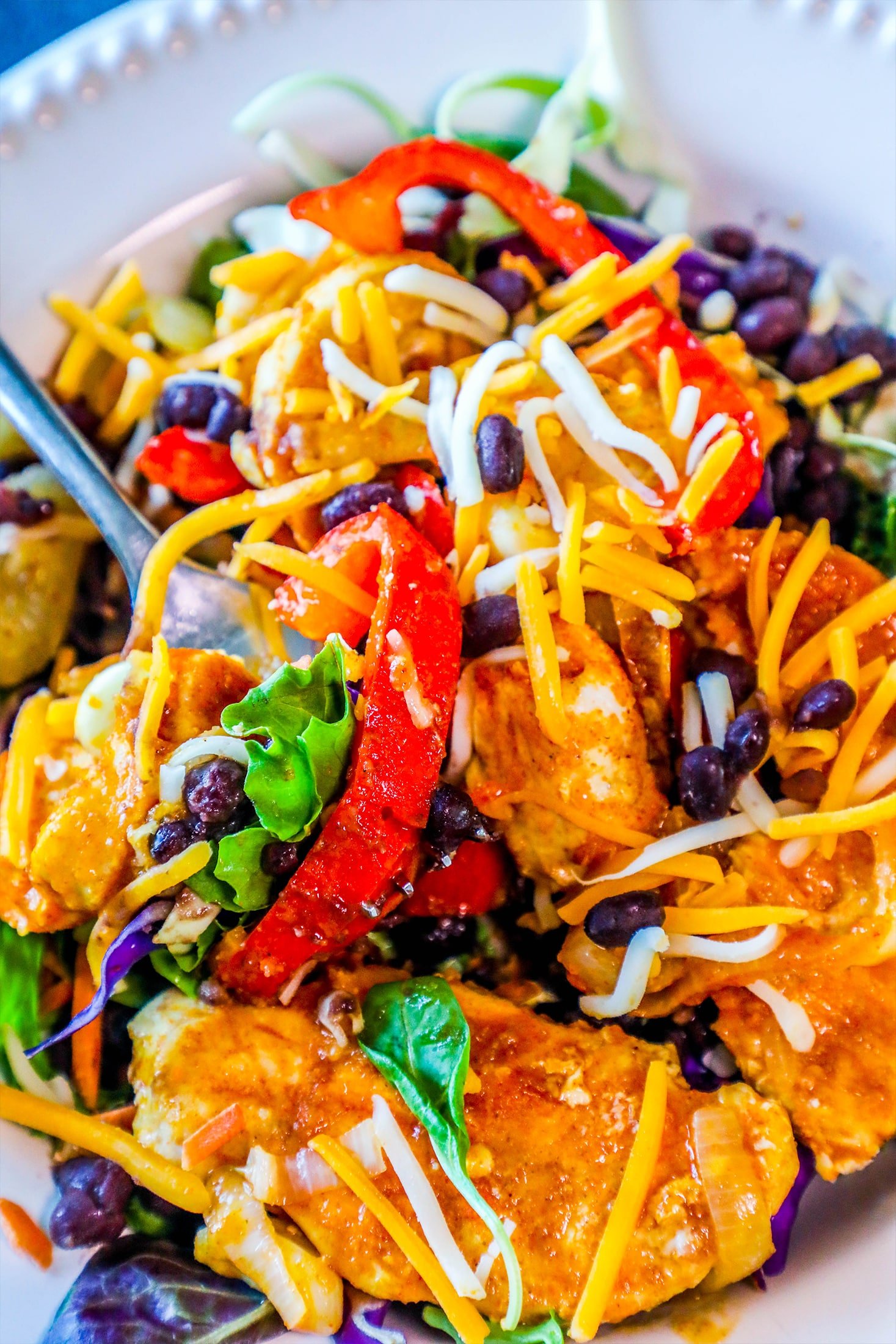 chicken, bell peppers, beans, cheese, lettuce, and lime on a white plate