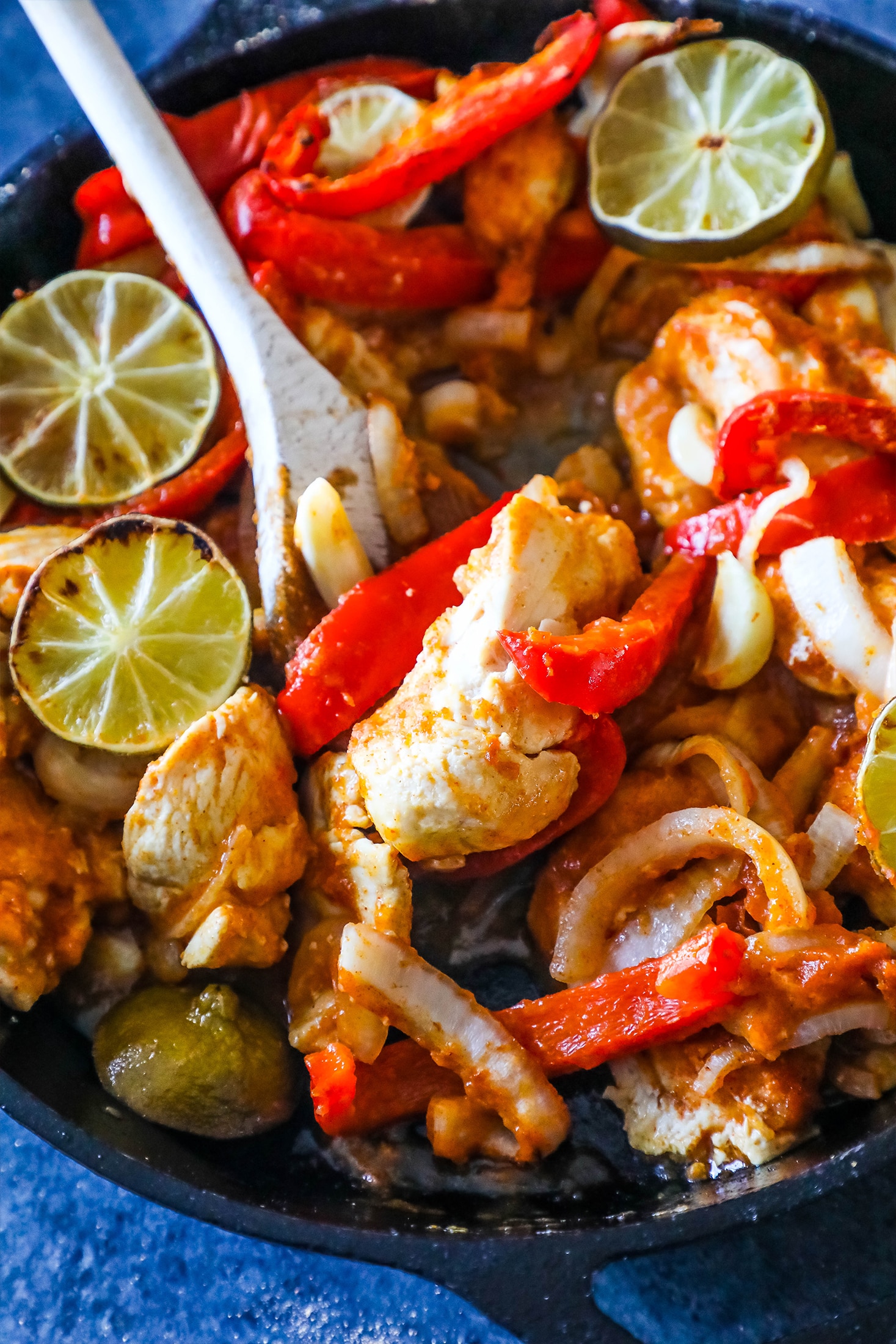 chicken, bell peppers, and lime in a pan with a spoon in it