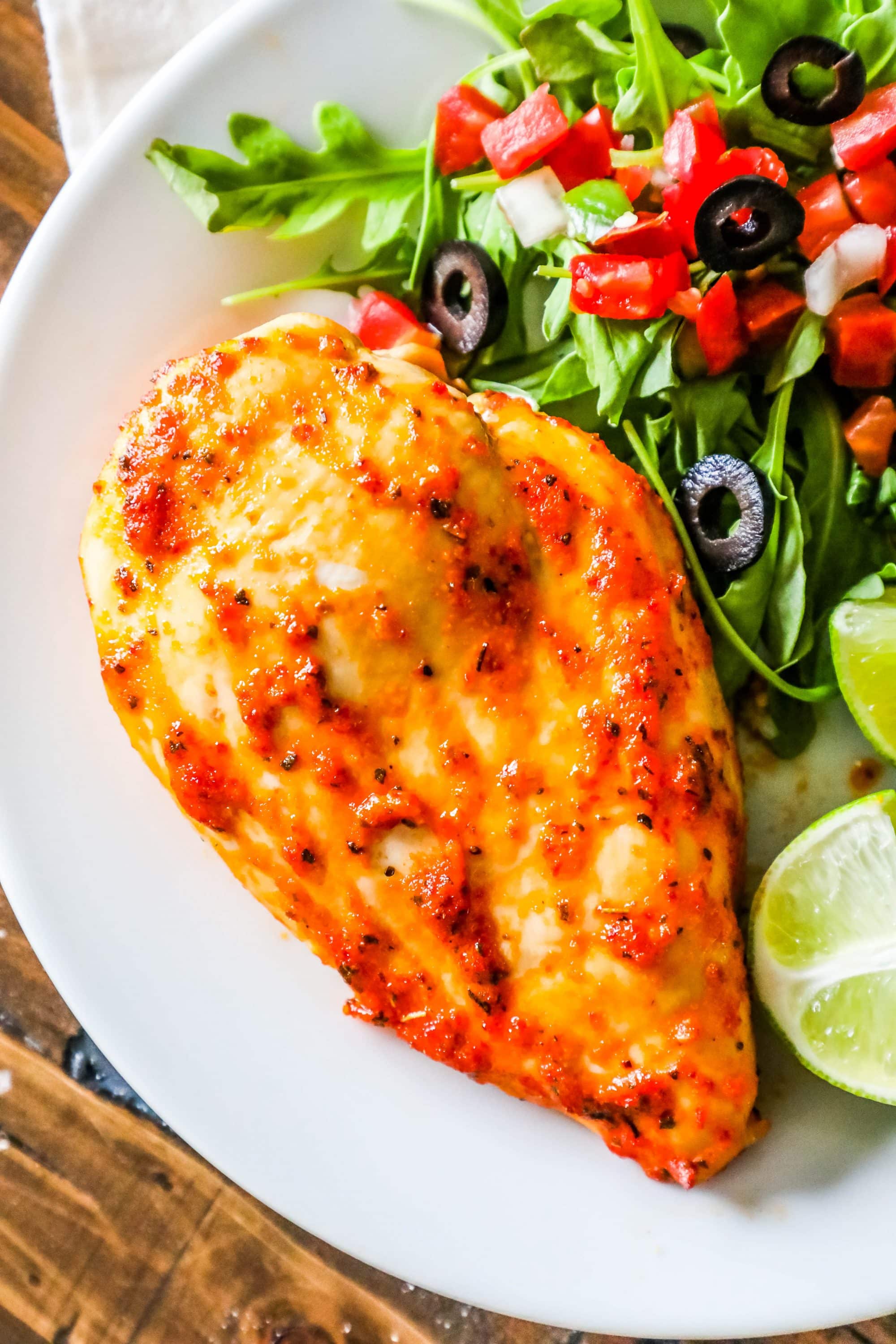 Oven roasted chicken breast served on a plate with a side salad.