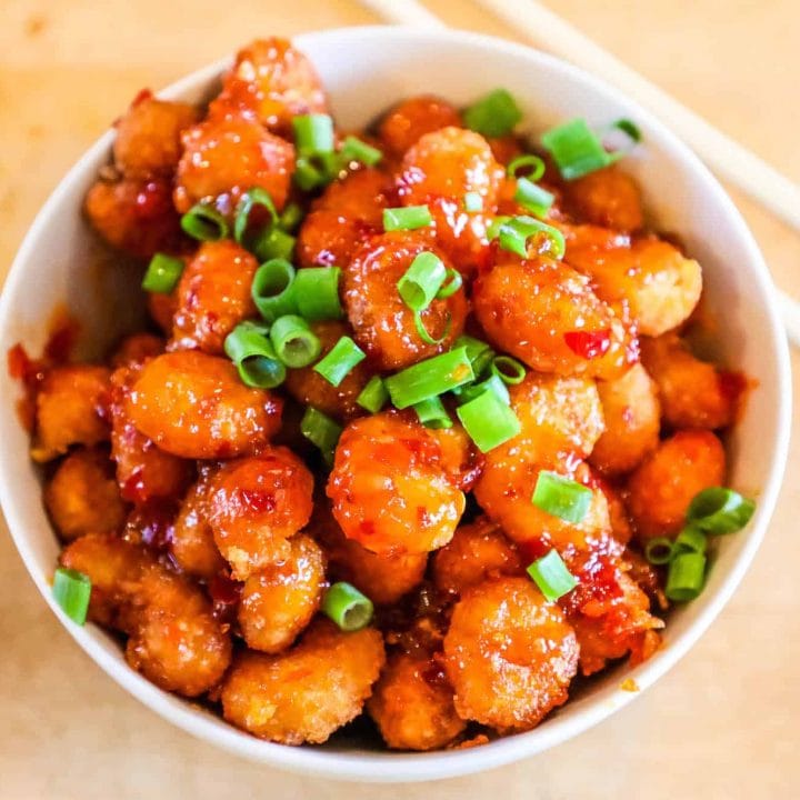Chinese chicken in a white bowl with Sriracha.