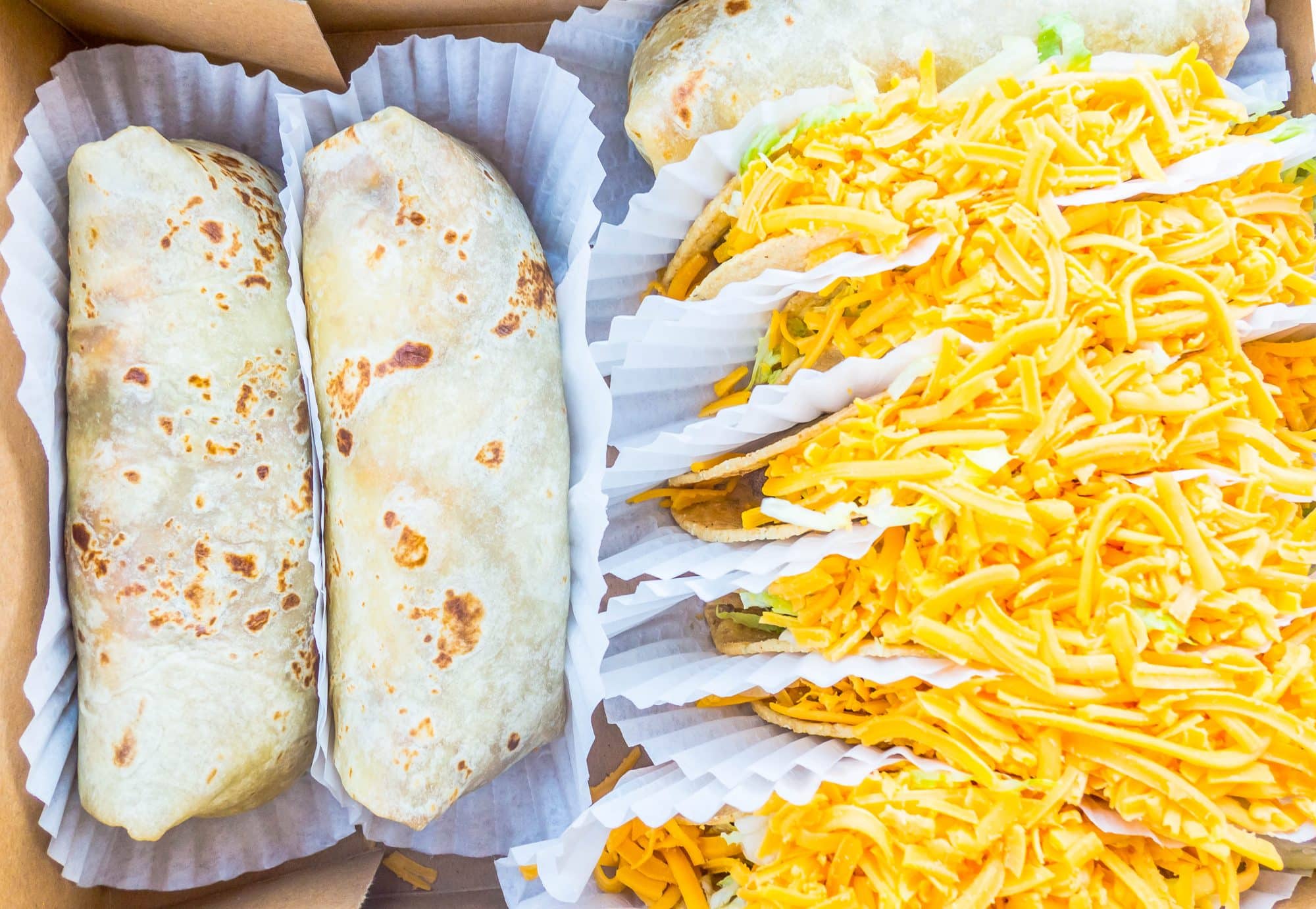 picture of burritos, tacos and salsa in a box 