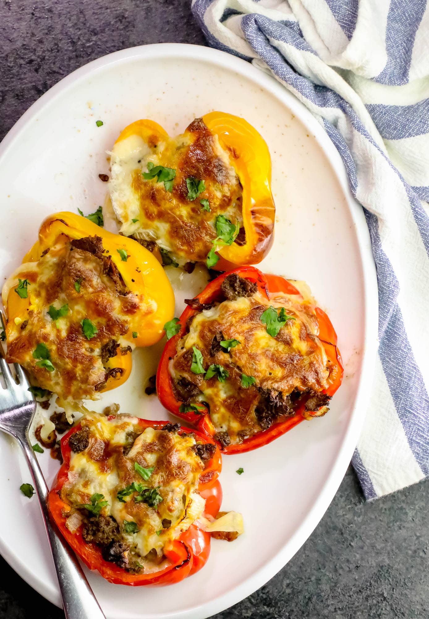 a plate with peppers with filling and melted cheese on top