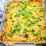 A casserole dish with black olives and green onions: Green Chile Enchilada Pie.