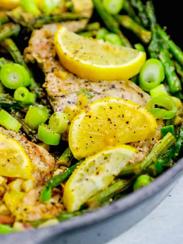 Chicken and asparagus cooked in a skillet with lemon slices, creating a one pot lemon garlic pork chop skillet meal.