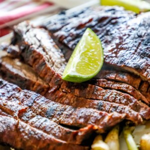 Spicy grilled flank steak with lime served on a white plate.