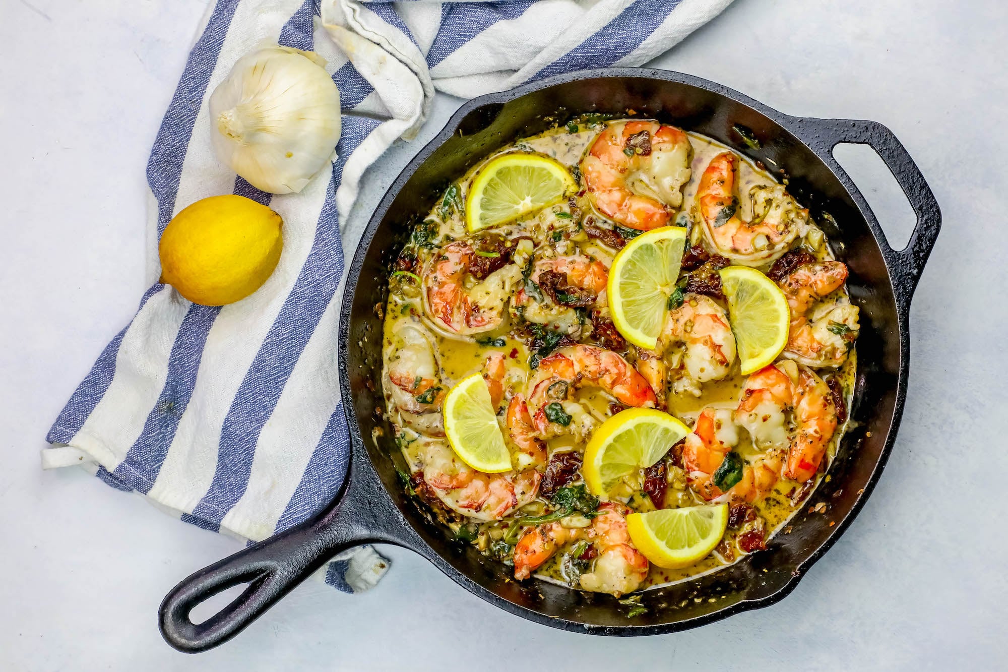 A cast iron skillet with shrimp and creamy lemon spinach.