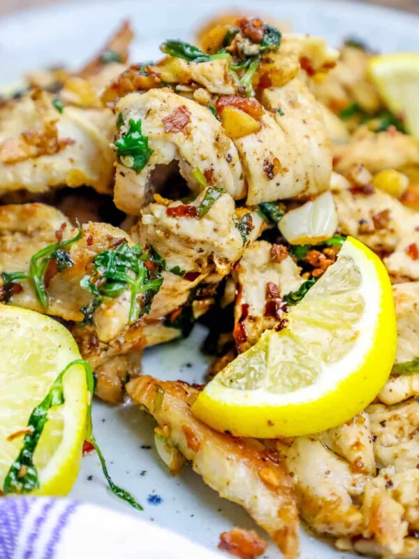 Grilled chicken tenders with lemon slices on a plate.