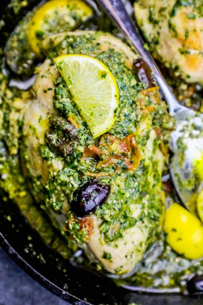 chicken covered in pesto and olives with a lemon slice on it