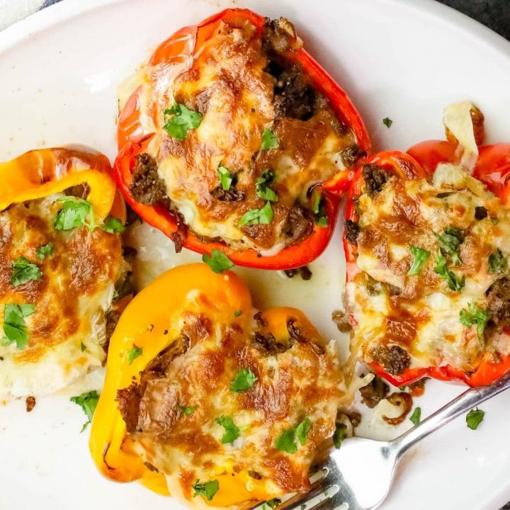 Baked Philly Cheesesteak Stuffed Peppers on a white plate with a fork.