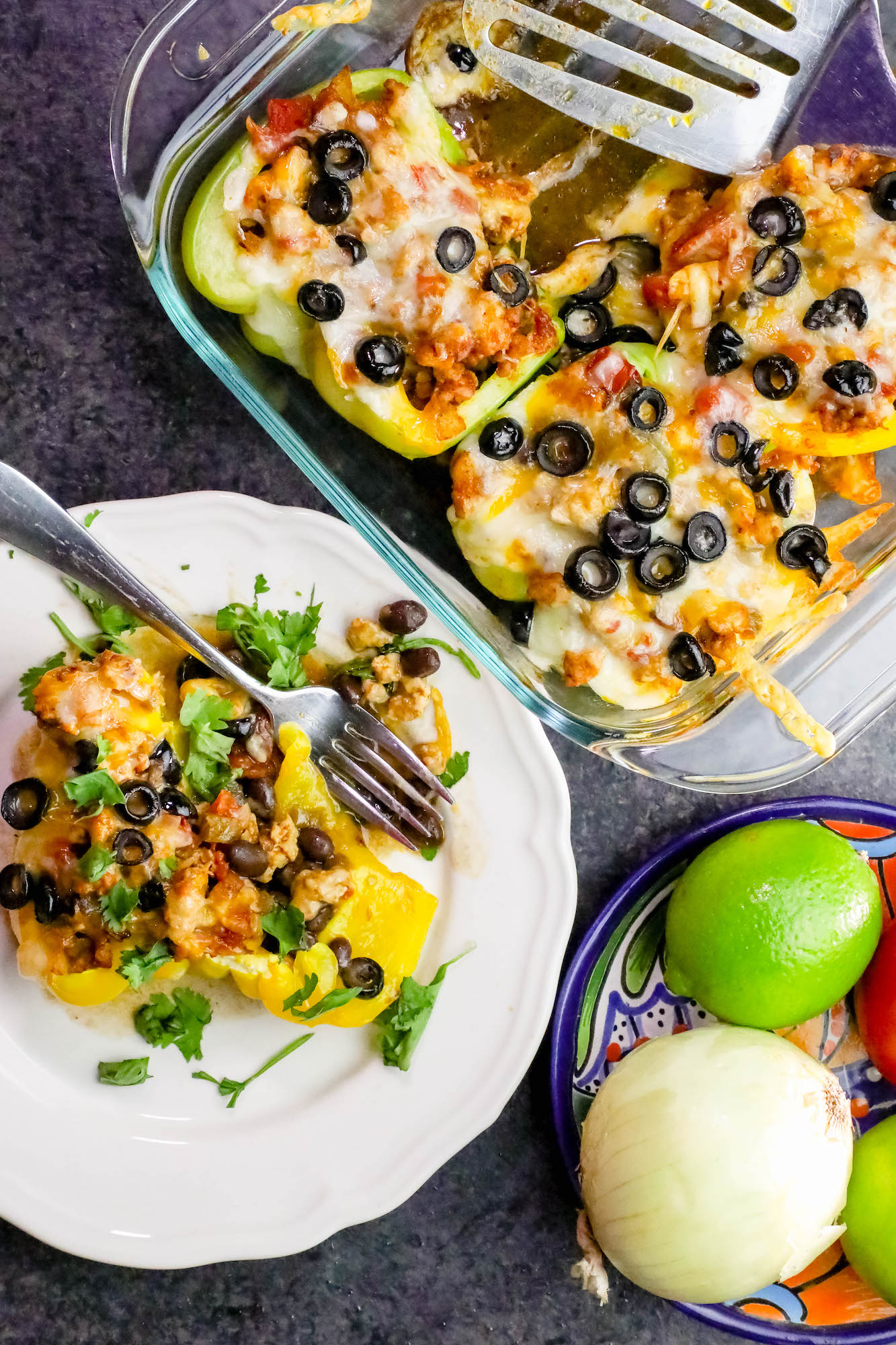 peppers in a casserole dish with cheese and black olives