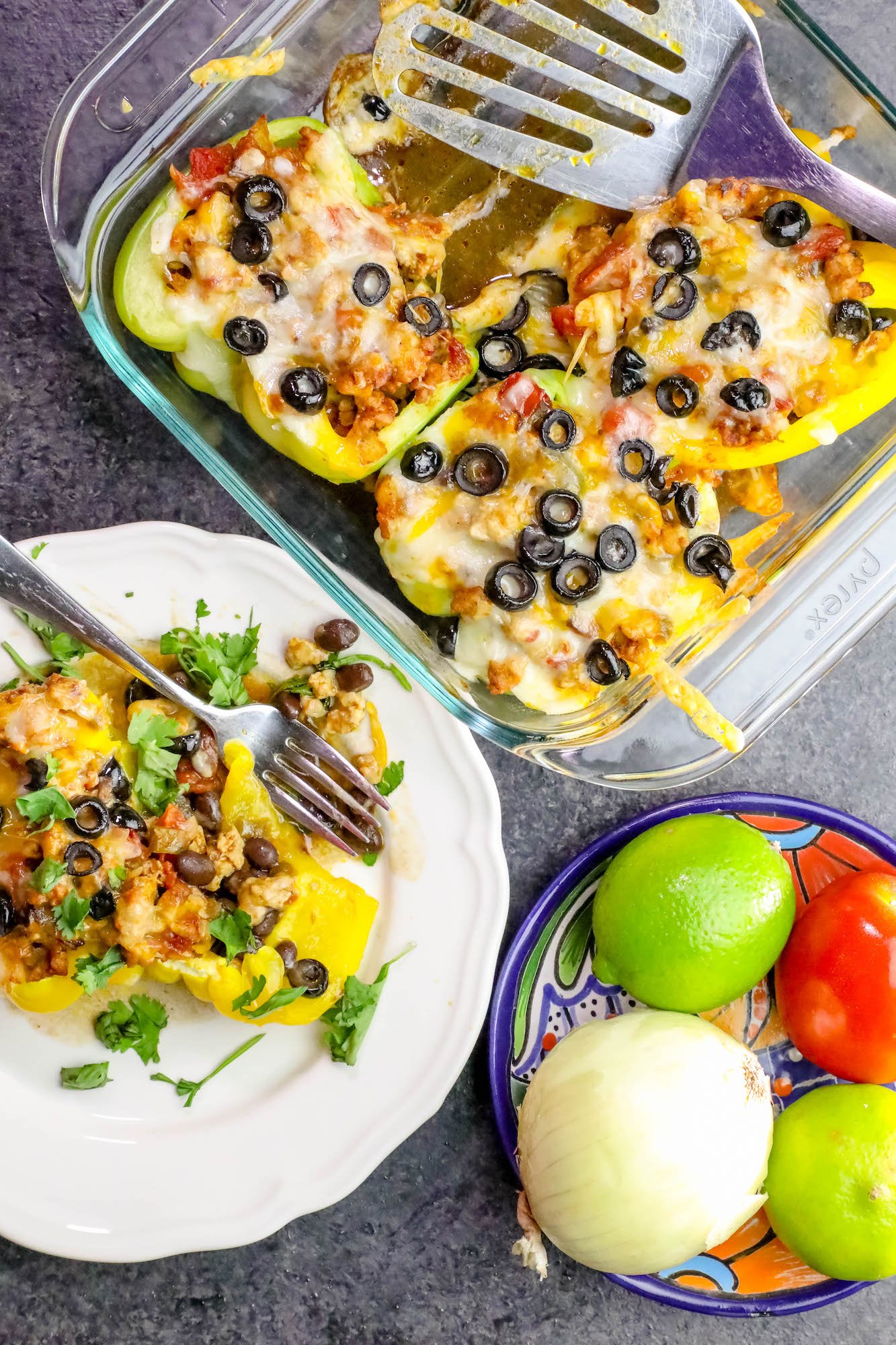 peppers in a casserole dish with cheese and black olives