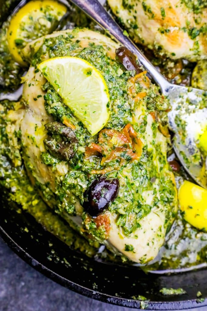 chicken covered in pesto and olives with a lemon slice on it