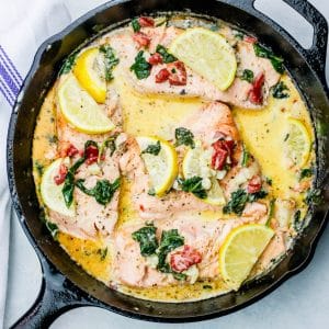 Lemon salmon with spinach in a skillet.