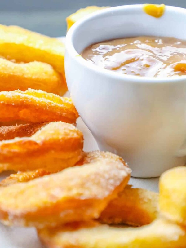 A plate of 2 Ingredient Easy Mulling Spice donuts with a cup of dipping sauce.
