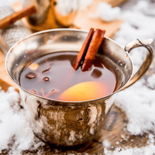 Mulled Elderflower Spiced Apple Cider in a silver cup with cinnamon sticks.