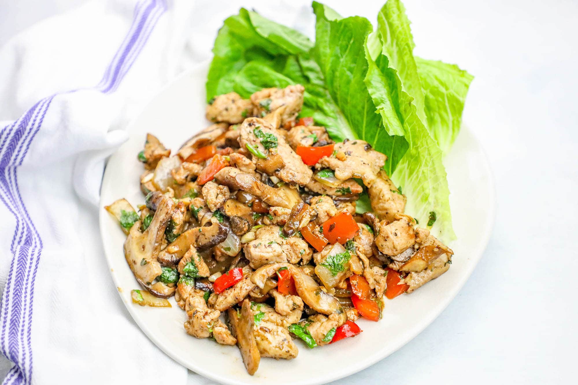 plate of pork diced up with peppers and seasoning on it and lettuce in the background