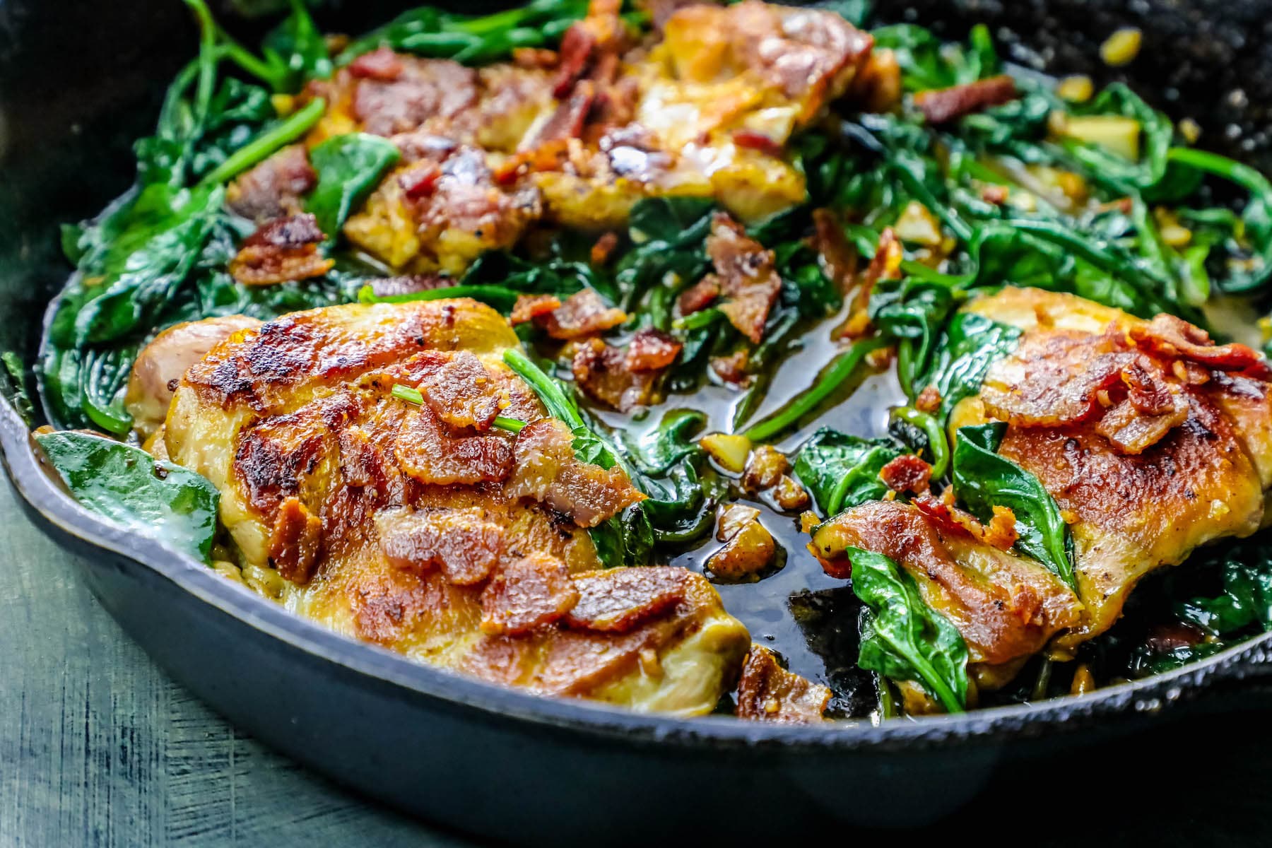 pan with chicken, bacon and spinach in it