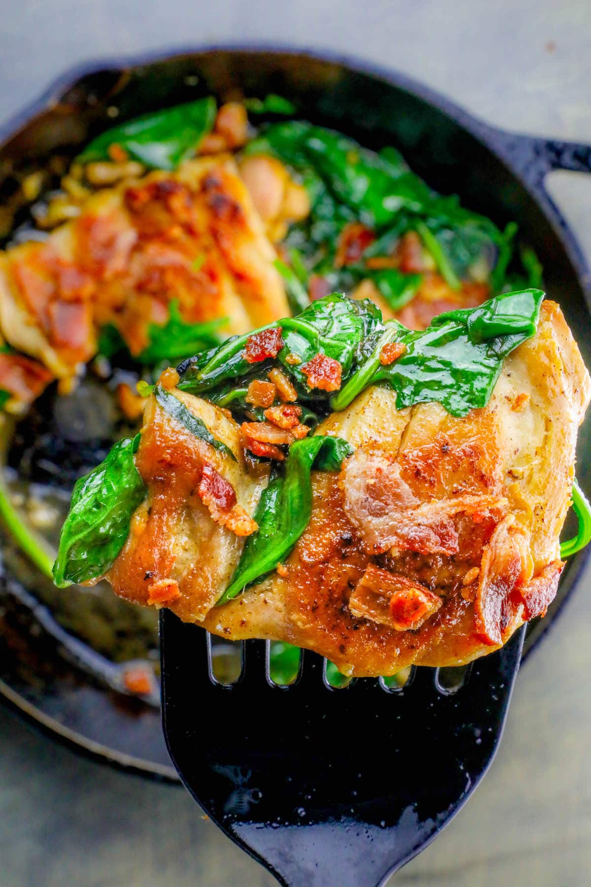 pan with chicken, bacon and spinach in it