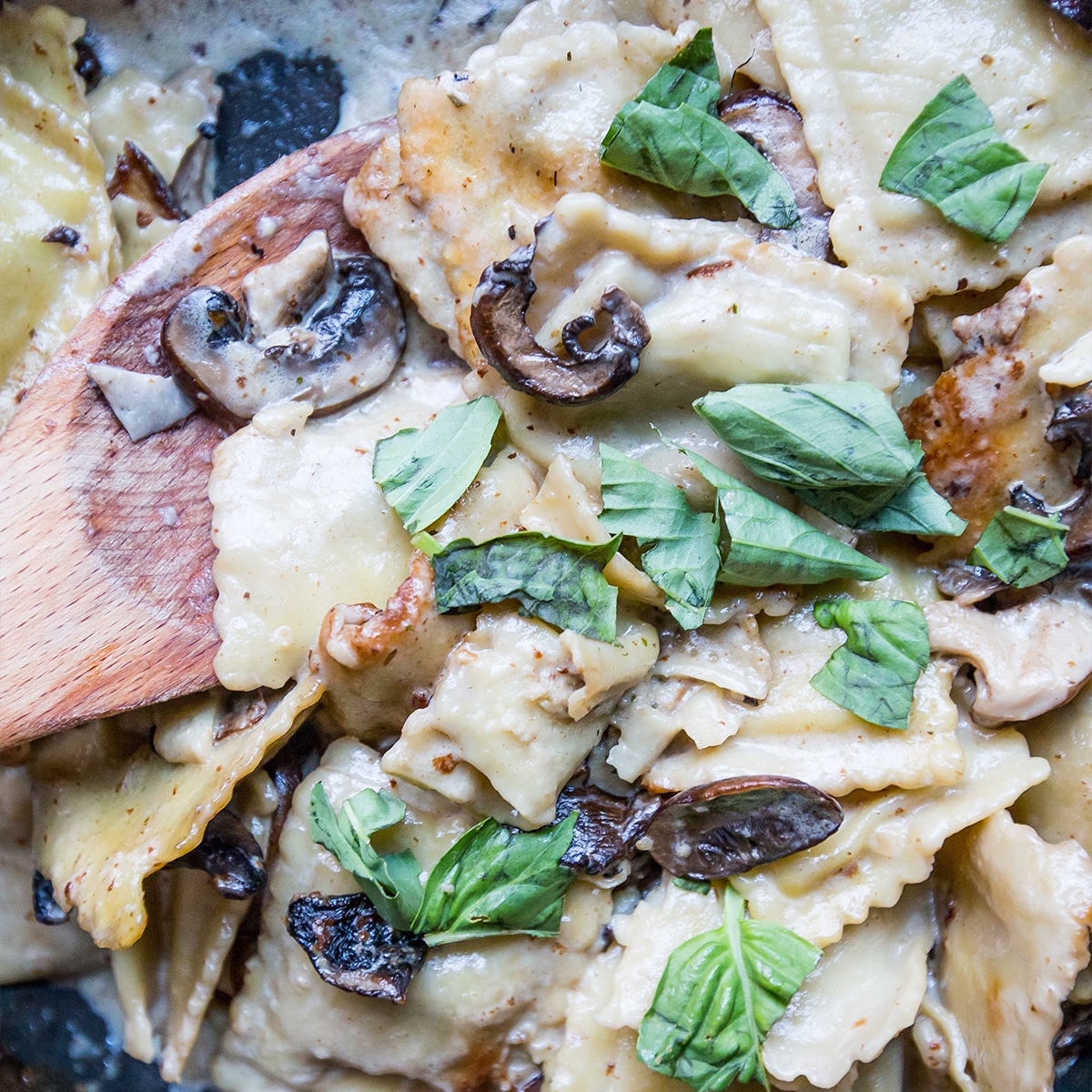 Beef ravioli stroganoff with mushrooms and basil cooked in a skillet.