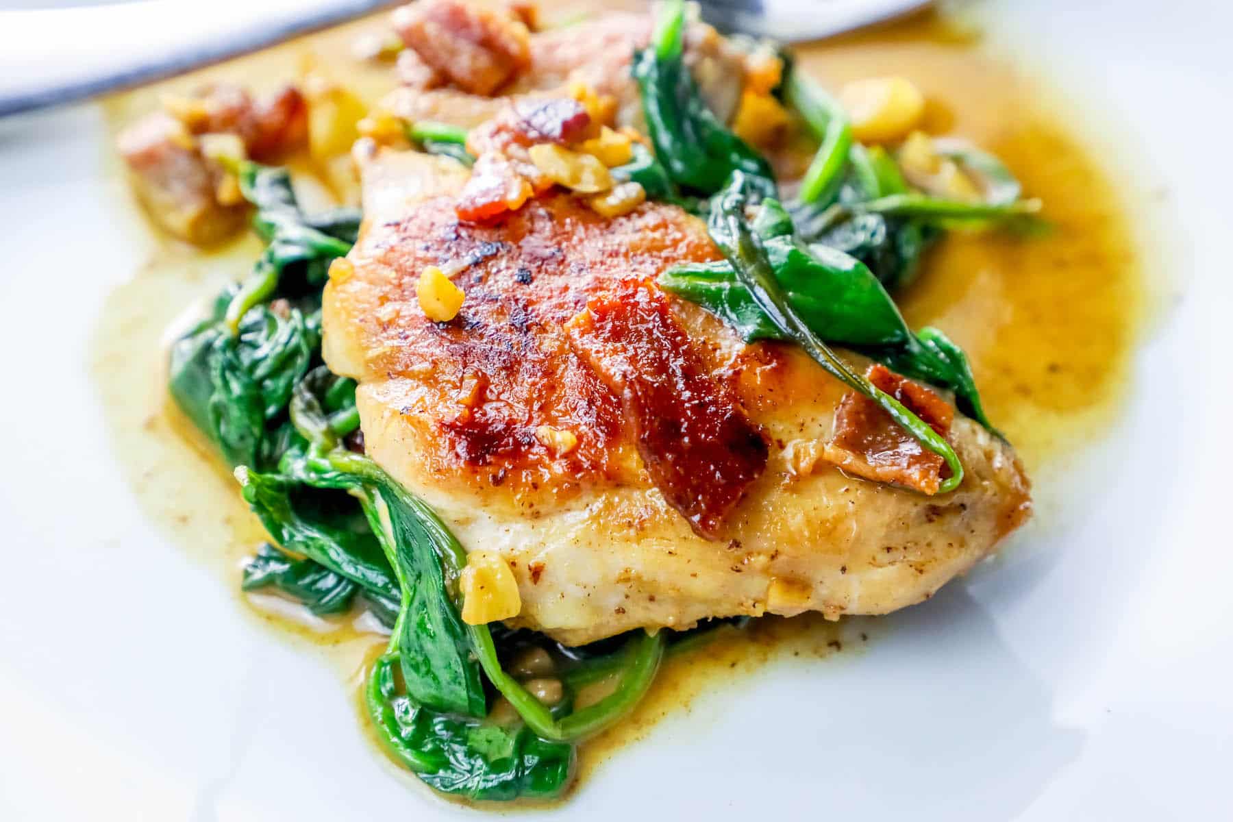 pan with chicken, bacon and spinach in it