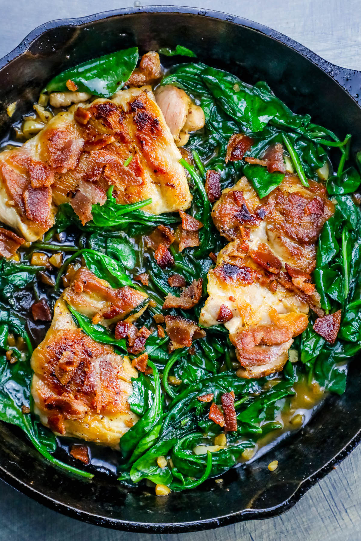 pan with chicken, bacon and spinach in it