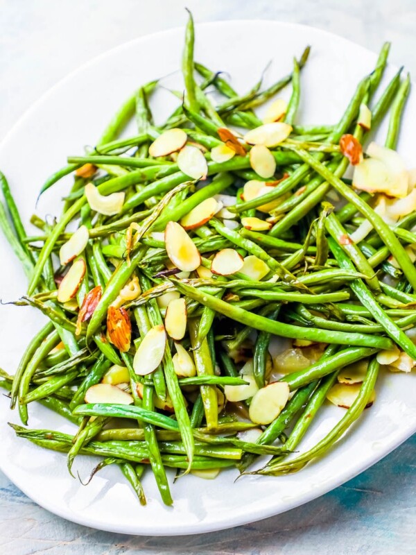 Roasted green beans almondine on a white plate.