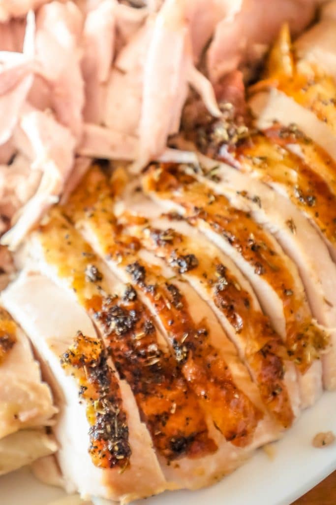 picture of sliced turkey breast covered with herbs on a white plate
