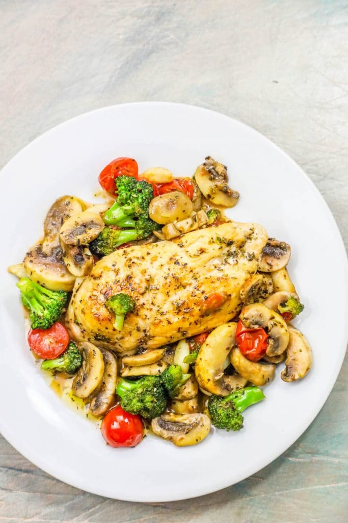 chicken in a bed of broccoli, tomato, and mushrooms and sauce