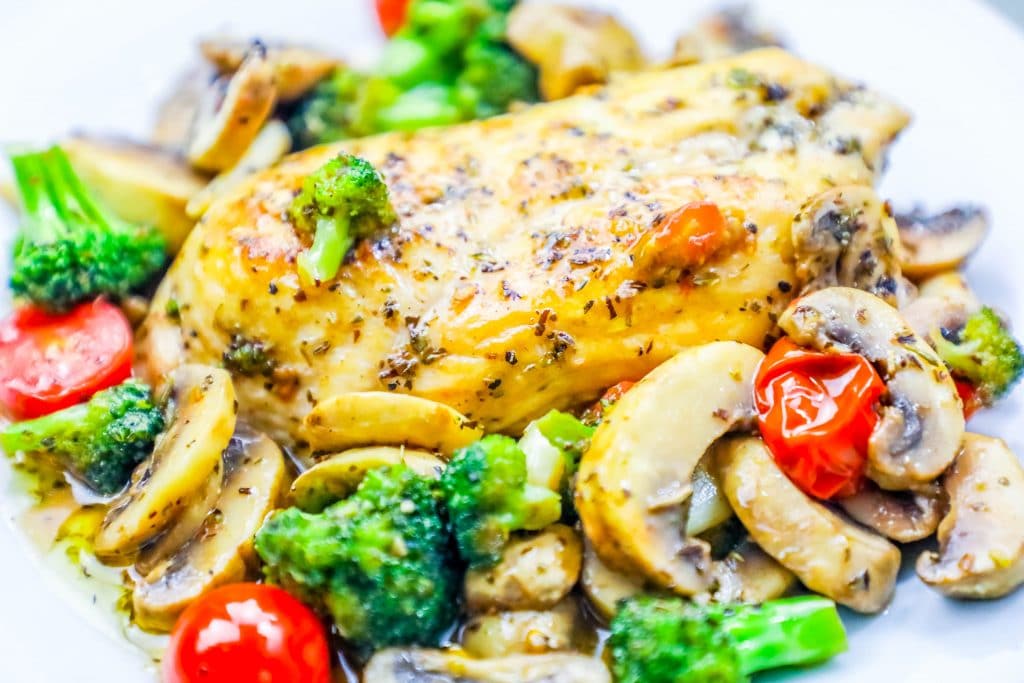 chicken in a bed of broccoli, tomato, and mushrooms and sauce