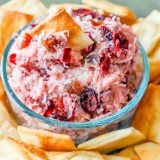A bowl of cranberry dip surrounded by crackers.
