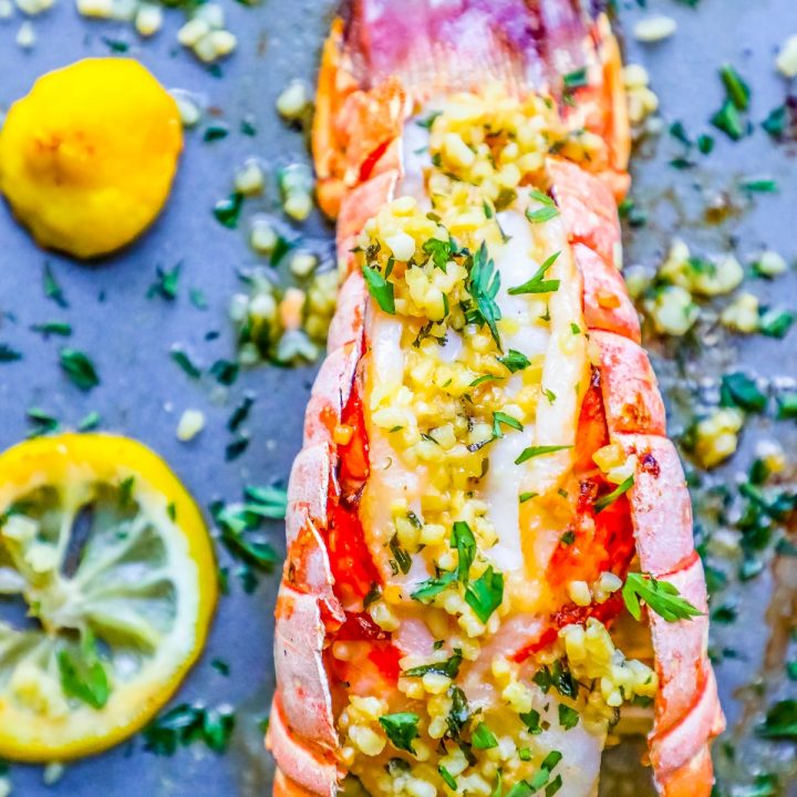 picture of lobster on baking sheet with lemon and parsley on top