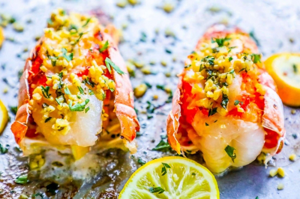 picture of lobster tails on baking sheet with lemon and parsley on top 