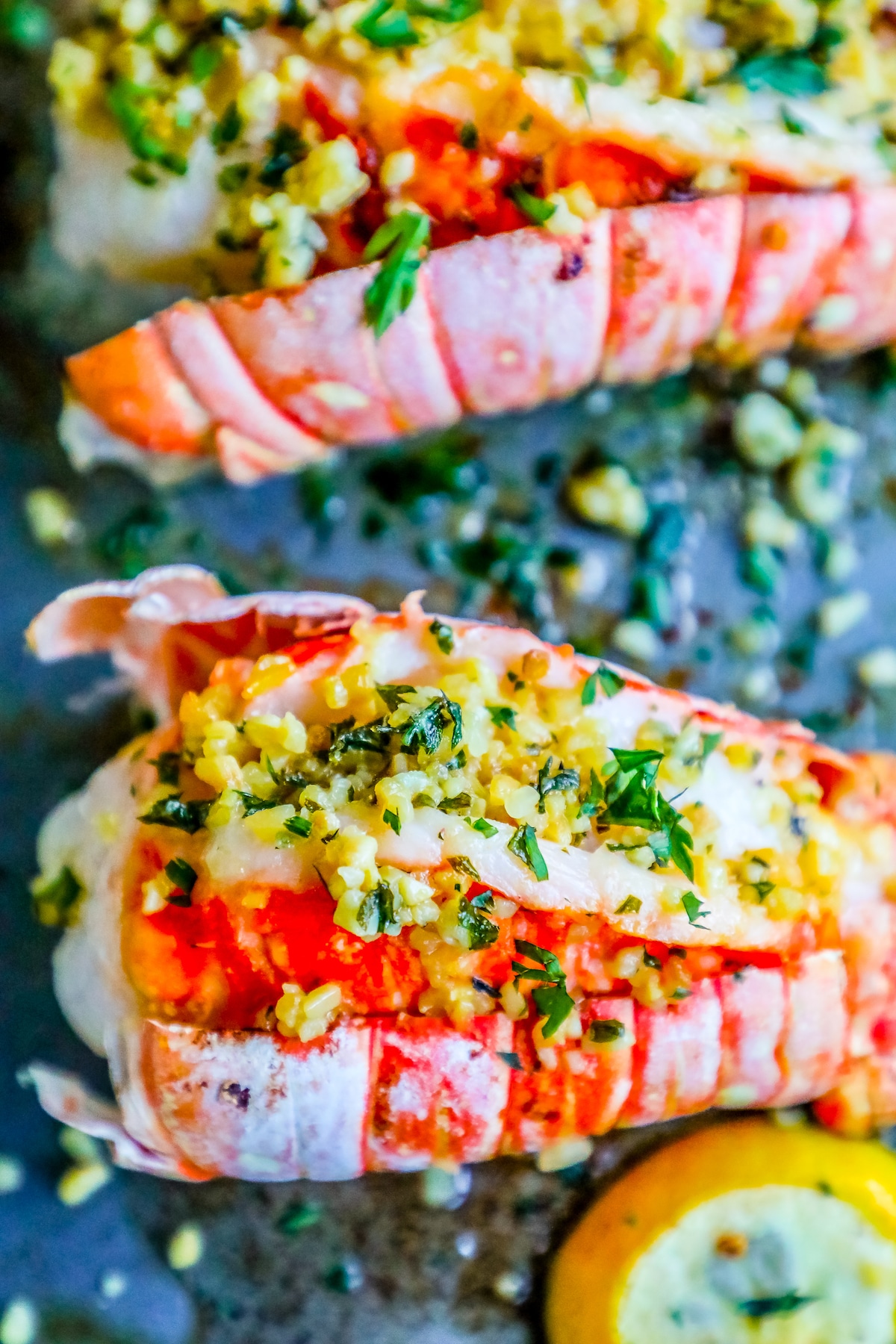 picture of lobster on baking sheet with lemon and parsley on top 