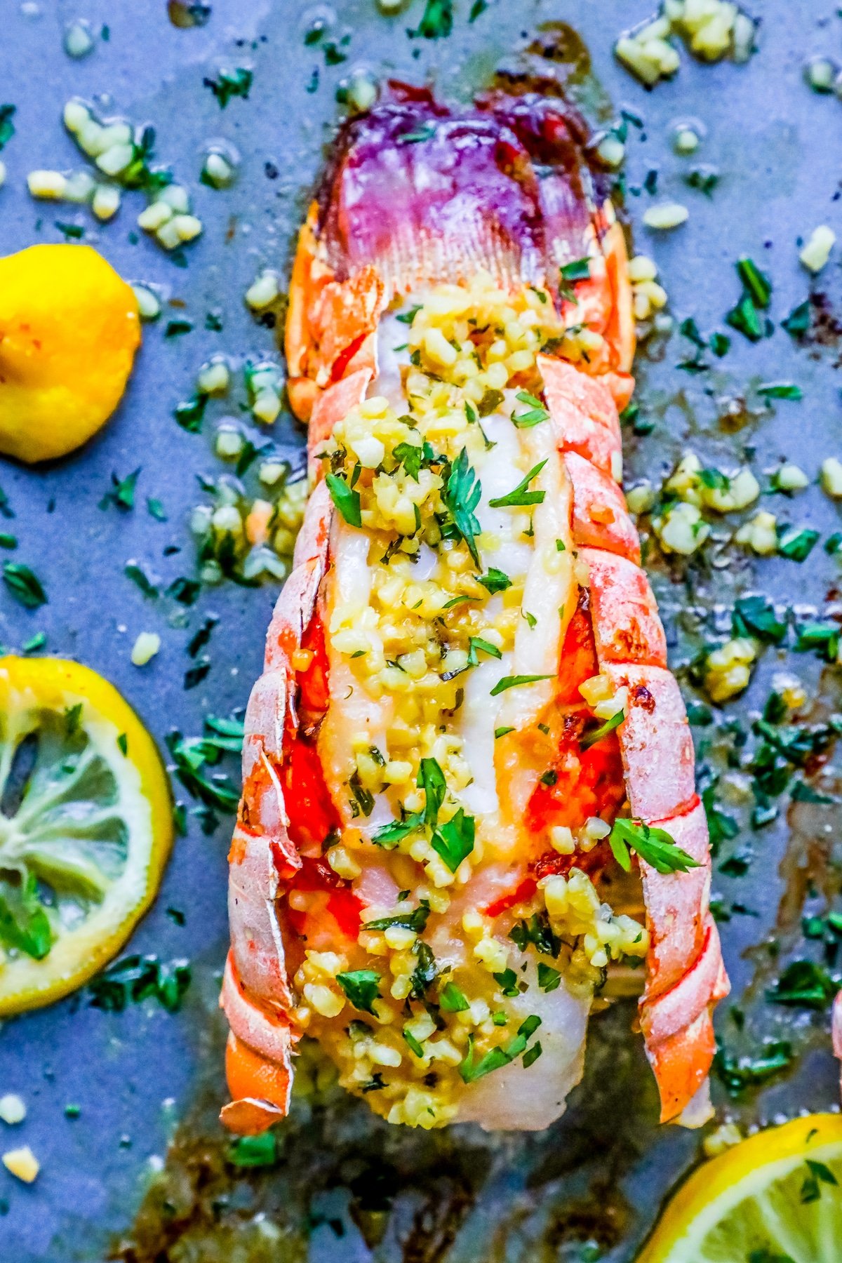 picture of lobster on baking sheet with lemon and parsley on top 