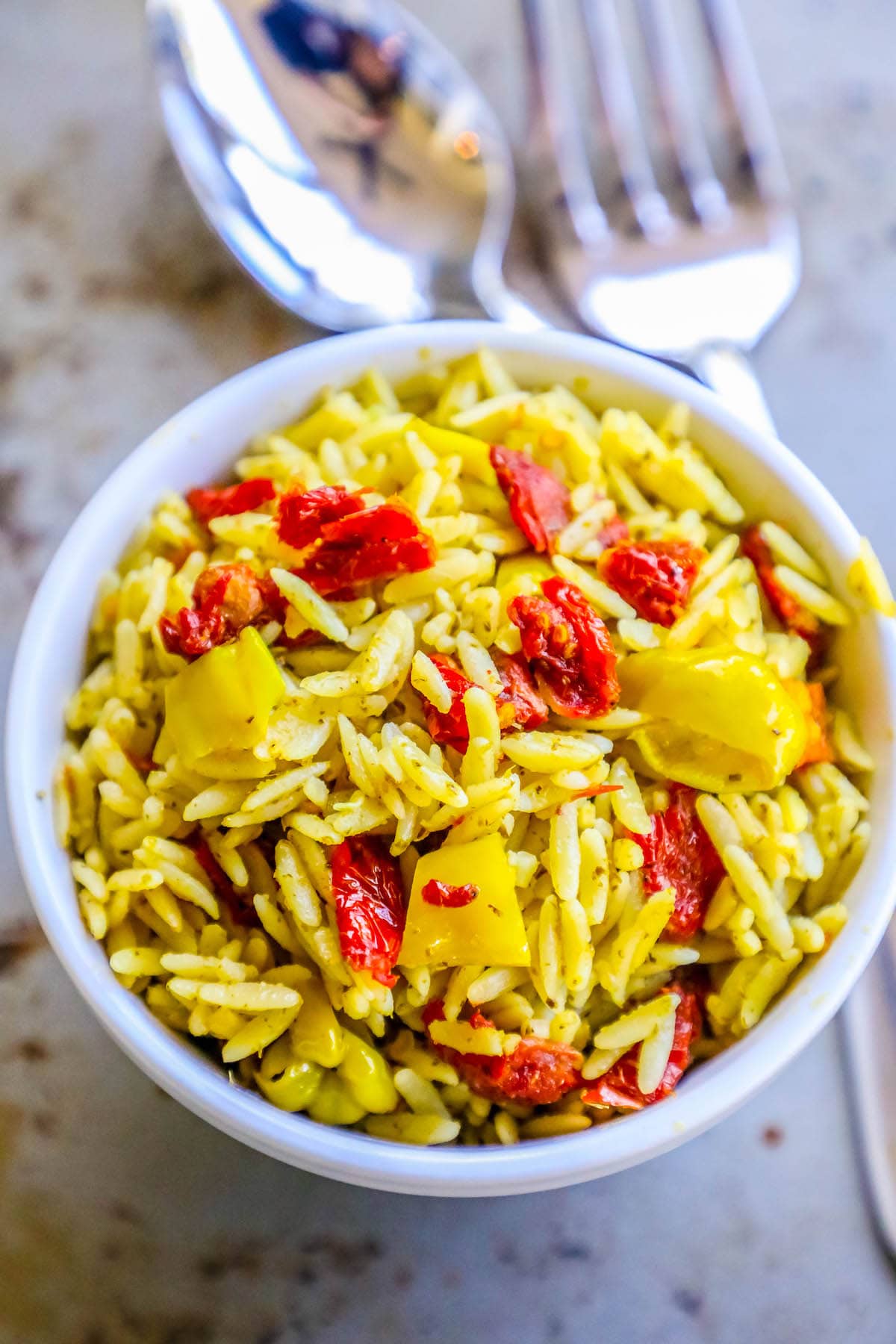 orzo in a bowl with sun dried tomatoes and yellow peppers