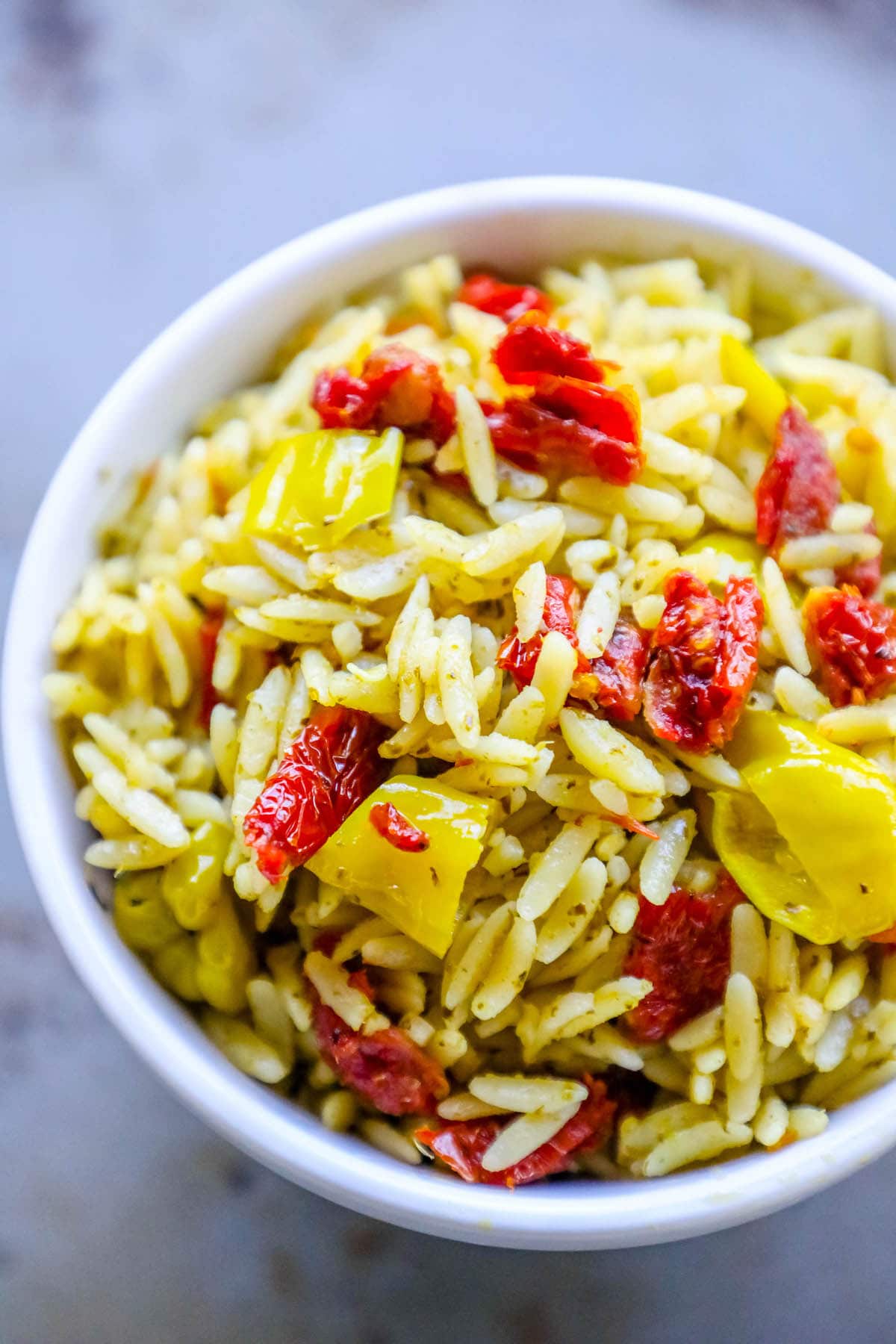 orzo in a bowl with sun dried tomatoes and yellow peppers
