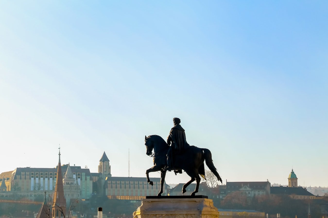 A statue of a man on a horse in front of Budapest, Hungary.