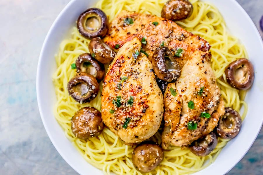 picture of chicken breast on pasta with mushrooms around it and spices