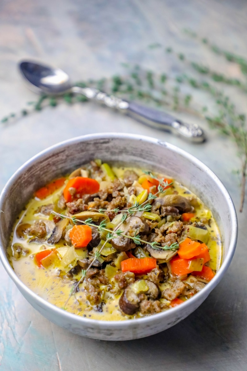 soup with sausage, carrots, mushrooms, onions, and thyme on it
