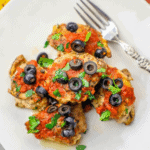 Chicken breasts topped with salsa and olives on a plate.